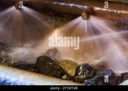 Unscharfer Fotohintergrund. Wasserstrahlen und Erzfelsen. Waschen von Golderz auf konzentrierende Pflanze. Khromtau, Mechel, Kasachstan. Stockfoto