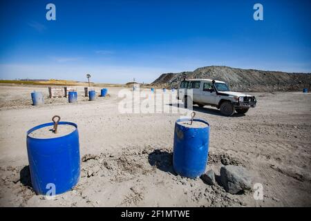 Khromtau, Region Aktobe, Kasachstan - Mai 06 2012: Goldmine. Handgemachte Straße Balustrade aus Kunststoff Fass mit Beton. Geländewagen im Hintergrund. Stockfoto