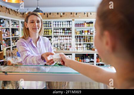 Weibliche Kundin Feinkostgeschäft Lebensmittelgeschäft Kauf Lokaler Käse Aus Dem Verkauf Assistent Stockfoto