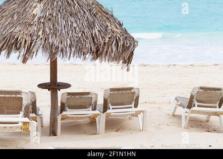 Liegestühle sind am Sandstrand unter Strohschirm, Dominikanische Republik Stockfoto