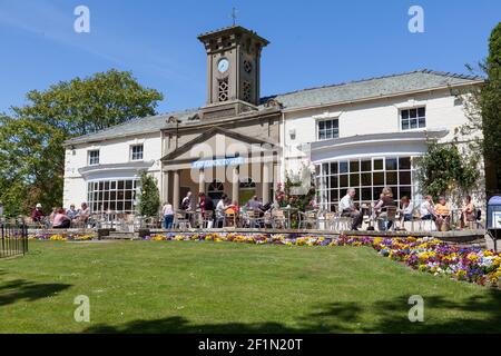 Besucher sitzen im Sonnenschein vor dem Clock Tower Cafe in Sewerby Hall in der Nähe von Bridlington, East Yorkshire Stockfoto