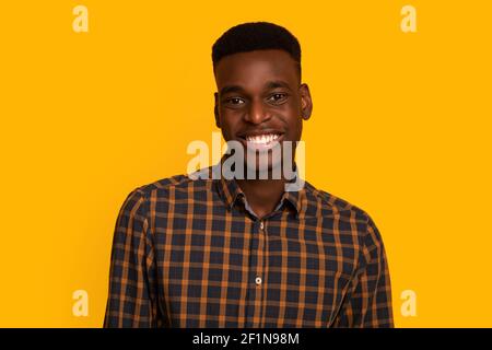 Porträt Von Positiven Afroamerikanischen Männlichen Studenten In Karierten Shirt Blick Und Lächeln An Der Kamera, Fröhlich Millennial African American Guy Stehend Stockfoto