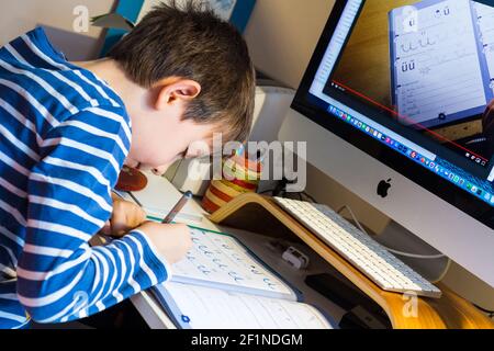 Fernunterricht, Lernen zu Hause während der Pandemie COVID-19. Junge Kind Briefe vor dem Computer schreiben, Ungarn, Europa Stockfoto