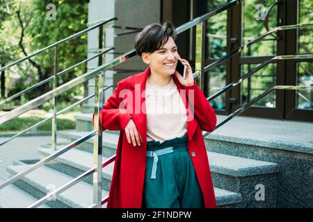 Young Business Professionals, gen z Frau arbeiten, erster Job, Praktikanten, Praktikum. Junge Brünette kurze Haare Geschäftsfrau mit sprechen Handy Stockfoto