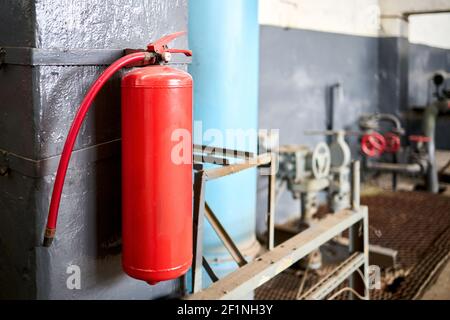 Feuerlöscher in der Fabrik für die Brandschutzanlage. Kohlendioxid-Feuerlöscher mit Manometer an der Wand des Produktionsraums Stockfoto