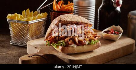 Leckere Schweineburger und Pommes auf Holz serviert Tisch mit Sauce auf schwarzem Hintergrund Stockfoto