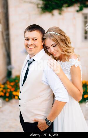 Die Braut umarmt Bräutigam auf den Straßen von Perast Neben weißen Backsteinhäusern Stockfoto