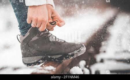 Mädchen binden Schuh Schnürsenkel auf den Schienen im Winter Stockfoto