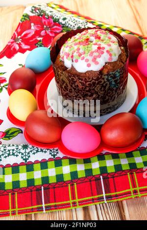 Osterteller mit Kuchen und bemalten Eiern auf einer hellen Tischdecke mit Blumendruck. Stockfoto