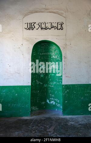 Eine grüne Nische an einer weißen Wand in einer islamischen muslimischen Moschee. Arabischer Text in schwarzen Buchstaben geschrieben Stockfoto