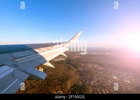 Flugzeug geht zur Landung. Blick vom Flugzeugfenster auf den Flügel während des Sonnenuntergangs Stockfoto