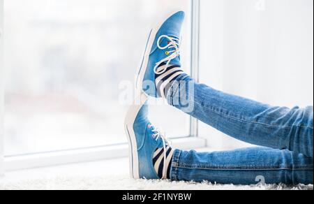 Beine in kühlen blauen Gummischuhen ruhen in hellen Raum Stockfoto