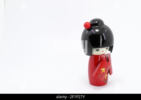 Japanische Holzpuppen 'kokeshi' in rotem Kimono-Anzug, Spielzeug für eine Dekoration, Souvenir aus Japan isoliert auf weißem Hintergrund. Stockfoto