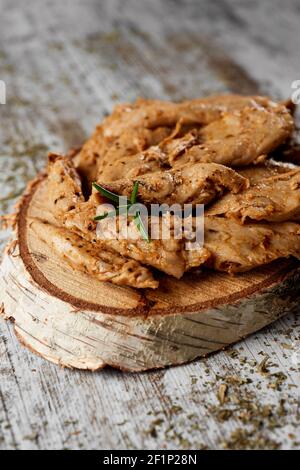 Nahaufnahme von einigen gekochten Streifen gewürzter Hühnerfleischstreifen auf einem Holztablett serviert, auf einem rustikalen Holztisch platziert Stockfoto