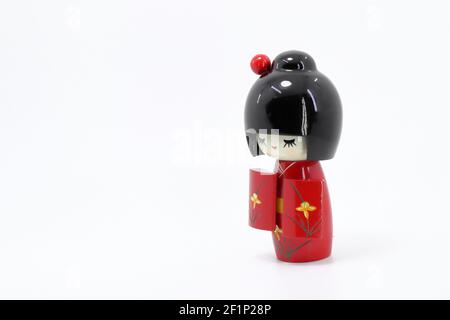Japanische Holzpuppen 'kokeshi' in rotem Kimono-Anzug, Spielzeug für eine Dekoration, Souvenir aus Japan isoliert auf weißem Hintergrund. Stockfoto