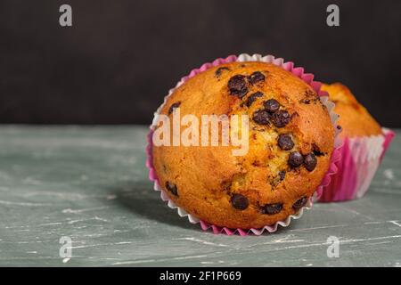 Cupcake mit Schokoladenstückchen in Nahaufnahme, Nahaufnahme auf grünem Hintergrund Stockfoto