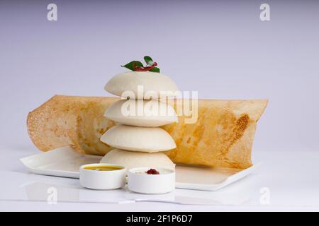 Ghee Roast Dosa und Idlii, südindisches Hauptfrühstück, das wunderschön auf einem weißen Teller mit Bananenblatt und Curry als Samba angeordnet ist Stockfoto