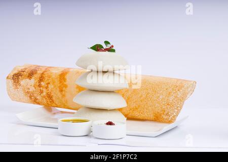 Ghee Roast Dosa und Idlii, südindisches Hauptfrühstück, das wunderschön auf einem weißen Teller mit Bananenblatt und Curry als Samba angeordnet ist Stockfoto