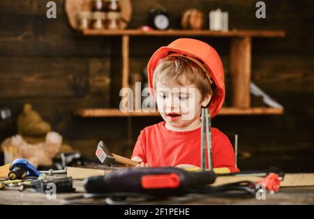 Aufgeregt Junge spielt mit Hammer. Kind hilft in der Werkstatt. Kleines Kind, das die Tischlerfertigkeit übt. Stockfoto