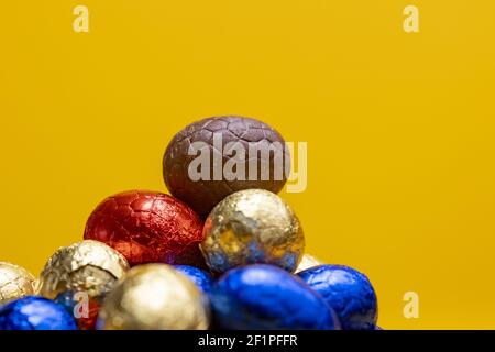 Mehrere kleine bunte eingewickelte Schokolade Osteier mit einem einzigen ausgepackt auf der Oberseite. Stockfoto