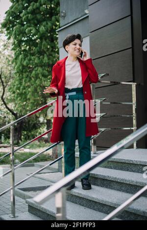 Young Business Professionals, gen z Frau arbeiten, erster Job, Praktikanten, Praktikum. Junge Brünette kurze Haare Geschäftsfrau mit sprechen Handy Stockfoto