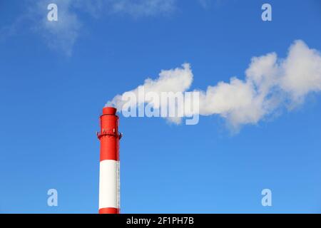 Fabrikkamin auf blauem Himmel Hintergrund mit weißem Rauch. Konzept der Dampfanlage, Luftverschmutzung, Heizperiode Stockfoto