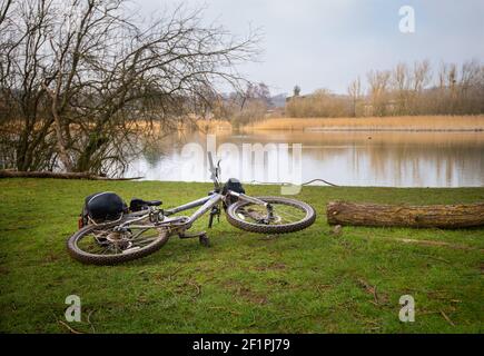 Fahrrad auf dem Boden neben klarem See am Wintertag in der Nähe Chartham in Kent Stockfoto