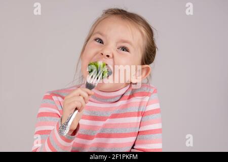 Das Kind isst Brokkoli mit unverstellter Ekel. Hochwertige Fotos Stockfoto