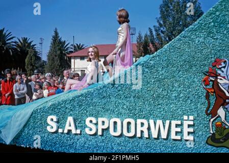 Paradewagen zur Förderung der Südafrikanischen Eisenbahn (Spoorweë in Afrikaans), während der Apartheid-Ära, Durban, Südafrika, 1966. Es gibt zwei Schönheitsköniginnen, die Kronen auf dem Wagen tragen. Es ist sehr viel ein weißes Publikum Betrachten dieses Ereignis. Dieses Bild ist von einem alten Amateur 35mm Kodak Farbtransparenz. Stockfoto