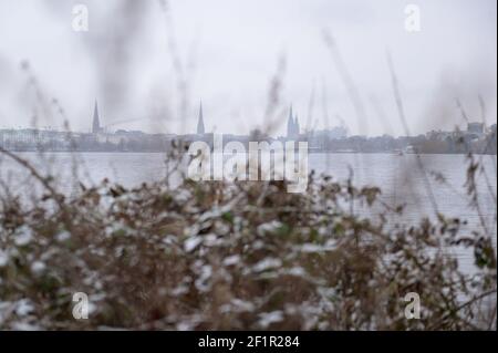 Hamburg, Deutschland. März 2021, 09th. Ein schneebedeckter Busch an der Außenalster vor dem Stadtpanorama mit Kirchen, Rathaus und Elbphilharmonie. Quelle: Jonas Walzberg/dpa/Alamy Live News Stockfoto