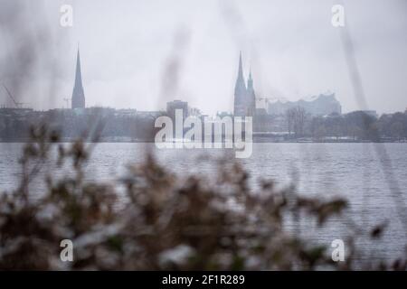 Hamburg, Deutschland. März 2021, 09th. Ein schneebedeckter Busch an der Außenalster vor dem Stadtpanorama mit Kirchen, Rathaus und Elbphilharmonie. Quelle: Jonas Walzberg/dpa/Alamy Live News Stockfoto