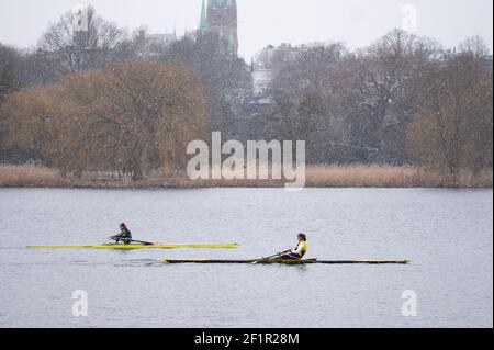 Hamburg, Deutschland. März 2021, 09th. Zwei Ruderinnen segeln in einer leichten Schneeregendusche vor dem Alsterpark und der Kirche St. Johannis Harvestehude auf der Außenalster. Quelle: Jonas Walzberg/dpa/Alamy Live News Stockfoto