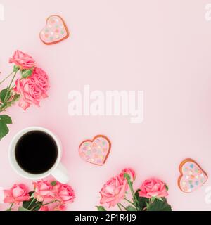 Lebensmittelkomposition mit Rosenblüten, Keksen und einer Tasse Kaffee auf rosa Hintergrund. Flach liegend, Draufsicht. Stockfoto