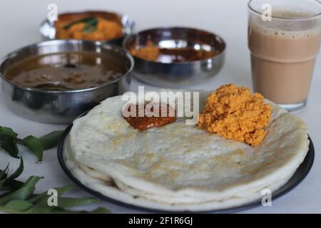 Indische Pfannkuchen werden auch als Dosa mit einem fermentierten Teig aus Reis und Linsen gemacht bekannt. Serviert mit idli podi chutney, sambar, Coconut Chutney und einem Glas Stockfoto