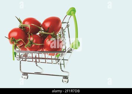 Nahaufnahme der roten Tomaten im Warenkorb auf türkisfarbenem Hintergrund isoliert. Stockfoto