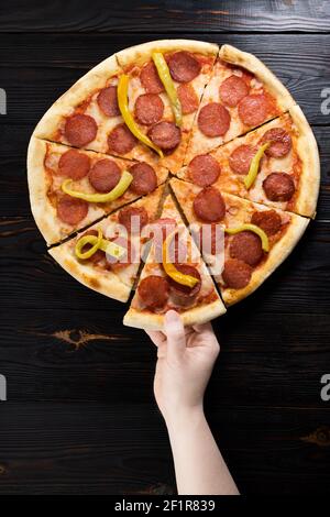 Die Hand der Frau nimmt ein Stück Pizza. Stockfoto