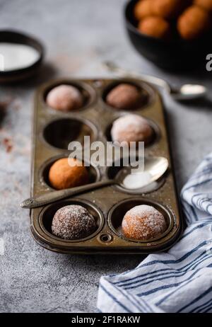 Nahaufnahme von Donut-Löchern mit Zucker in einer Backform bedeckt. Stockfoto