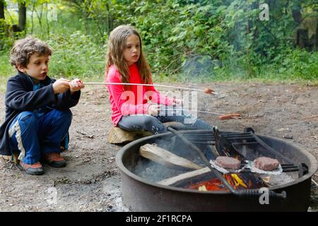 Zwei Kinder, die während des Campens Hot Dogs rösten Stockfoto