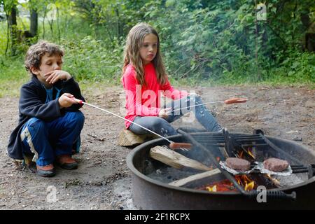 Zwei Kinder, die während des Campens Hot Dogs rösten Stockfoto