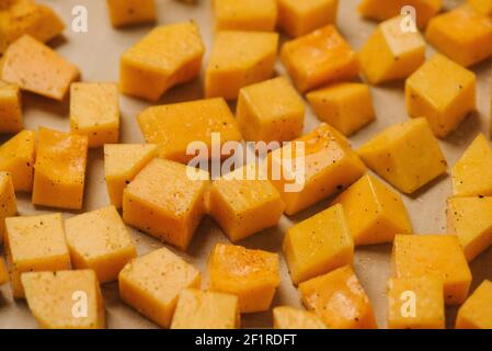 Geölte und gewürzte Stücke Butternusskürbis auf einem Backen Blatt Stockfoto