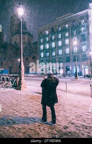 Junger Mann, der den Schneefall mit seinem Telefon in den Straßen von Madrid, Spanien, fotografiert. Stockfoto