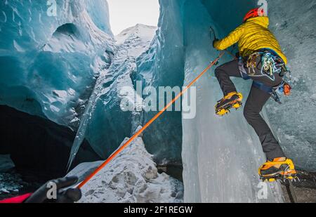 Mann klettert Eiszapfen in der Gletscherhöhle in Island Stockfoto