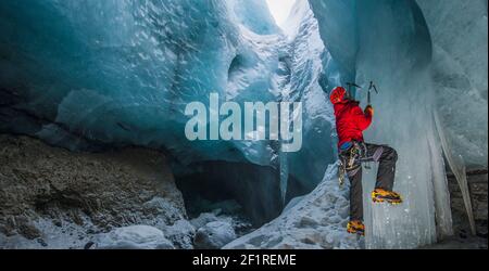 Mann klettert Eiszapfen in der Gletscherhöhle in Island Stockfoto