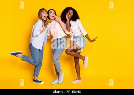 Foto in voller Größe von schönen optimistischen drei Damen Tanz-Look Leerer Raum tragen weißes Hemd Jeans isoliert auf gelbem Hintergrund Stockfoto