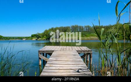 Lange alte hölzerne Pier und schöner See. Leer auf kleinem Landsee. Des Sommers. Platz für Text und Angeln Stockfoto