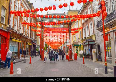 Menschen mit Schutzmasken gehen während der Coronavirus-Pandemie entlang der Gerrard Street, Chinatown im Zentrum Londons. Stockfoto