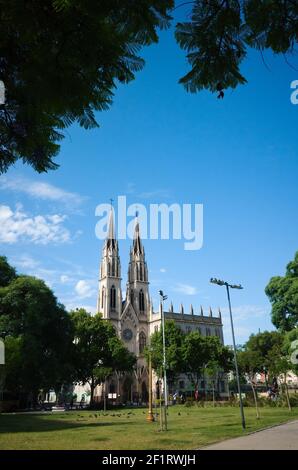 Buenos Aires, Argentinien - Januar, 2020: Grüner Rasen im öffentlichen Park namens Plaza de la Constitucion und neogotische Kirche Stockfoto