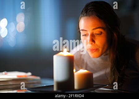 Schöne Frau, die Kerzen im Wohnzimmer ausblasen Zuhause in der Nacht Stockfoto