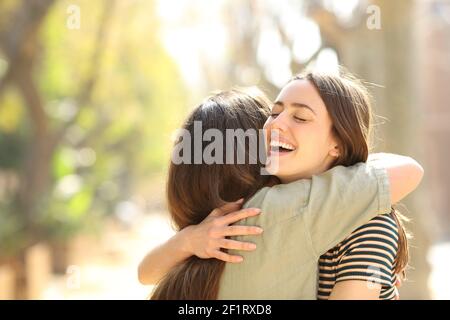 Zwei glückliche Frauen umarmen nach dem Treffen in der Straße A Sonniger Tag Stockfoto