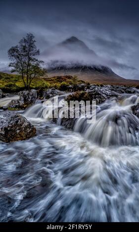 Dramatischer Wasserfall in Glencoe Scotland. Glen Etive in den schottischen Highlands fotografierte an einem stürmischen Tag mit schwerem Niedrigwolken in Schottland Großbritannien Stockfoto